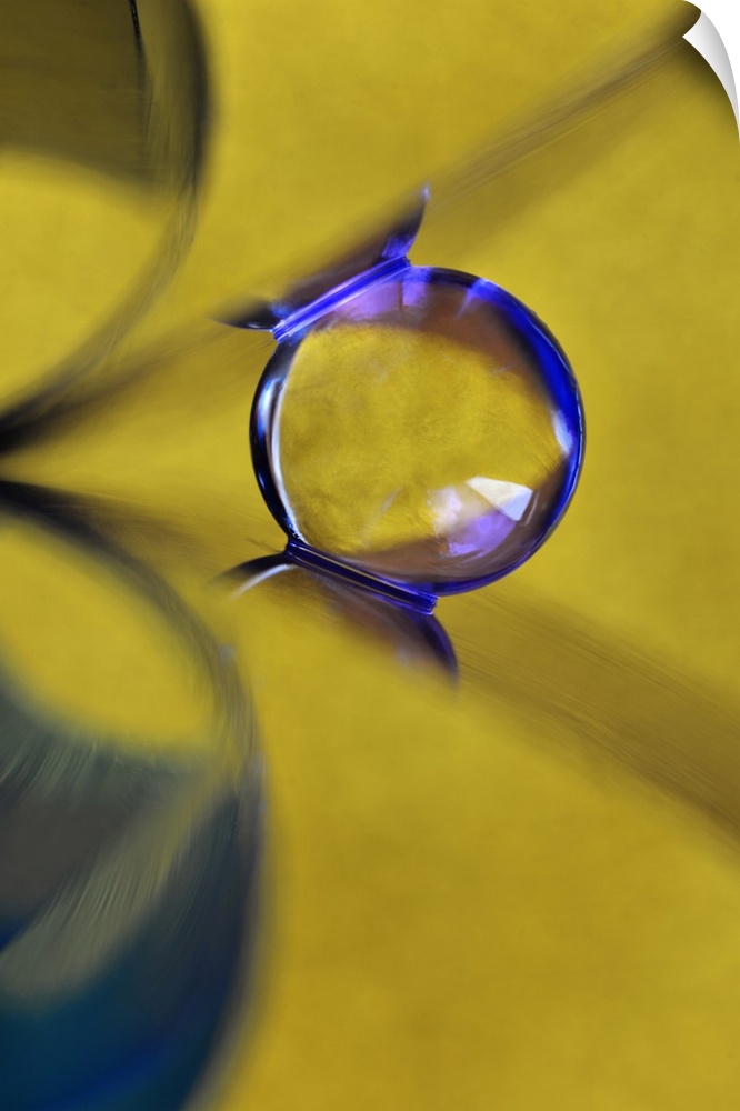 Macro abstract photograph of a water droplet reflecting on a yellow surface.