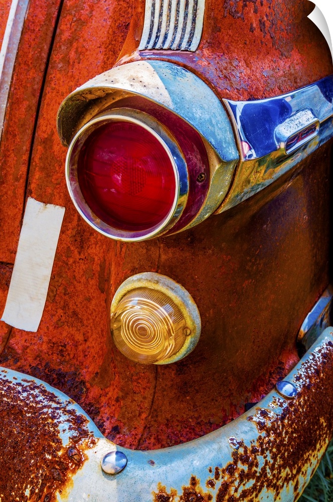 A vivid surrealistic rusty red antique Pontiac tail light section with red and yellow lenses and blue reflections in its c...