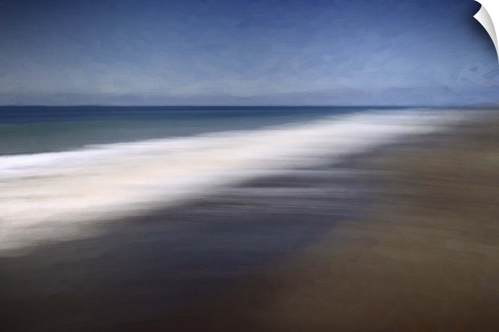 Blurred long-exposure image of the foamy sea on a sandy beach, moving with the tide.