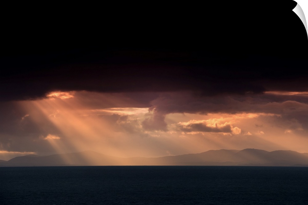 Fine art photo of beams of light coming from dark clouds over a lake.