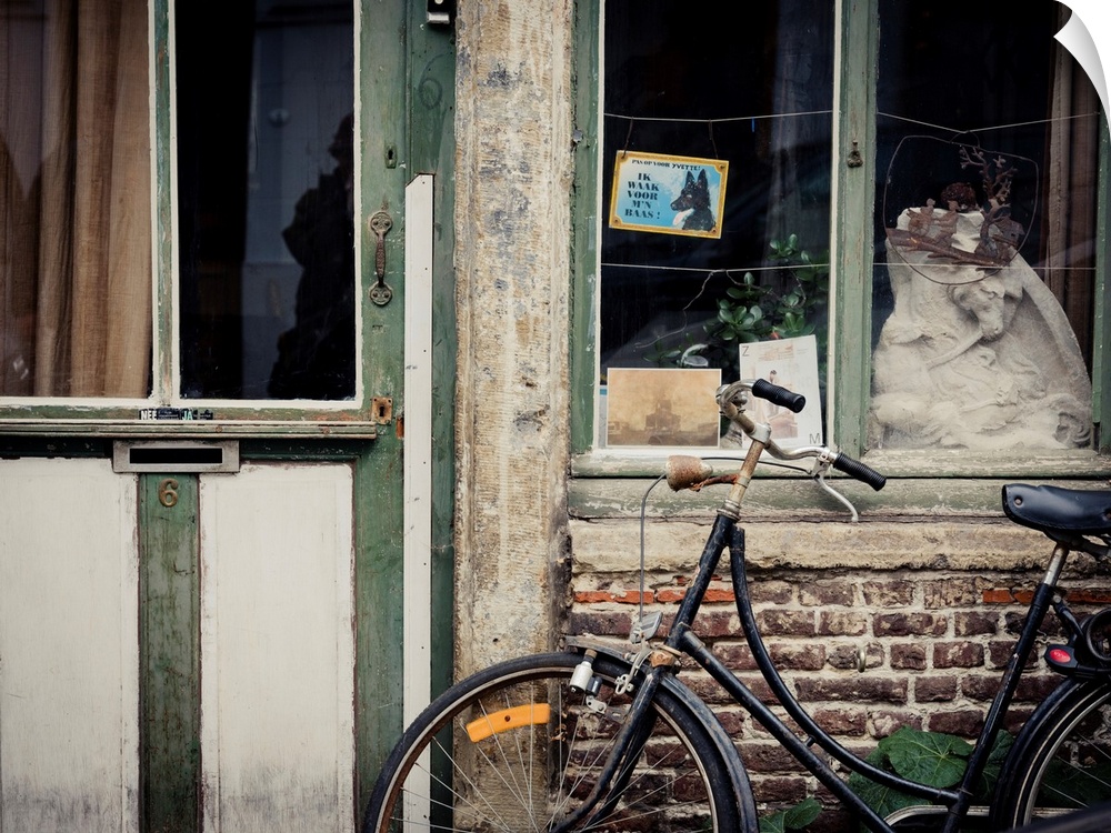 A photo of an aged building with a bicycle and a beware of dog sign in dutch out front.
