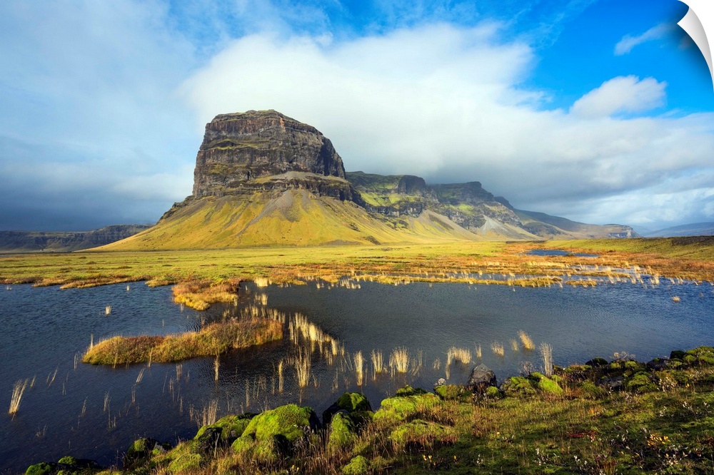 Fine art photograph of the Icelandic landscape with a tall mountain surrounded by clouds.