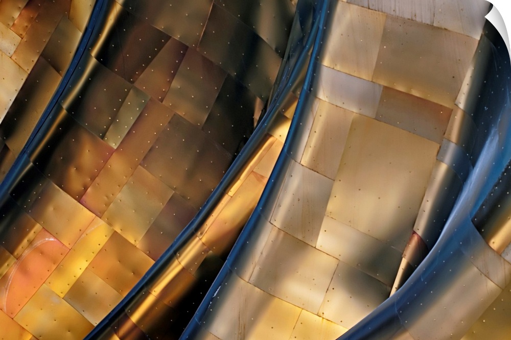 Abstract photograph of a large metal structure reflecting blue and gold light.