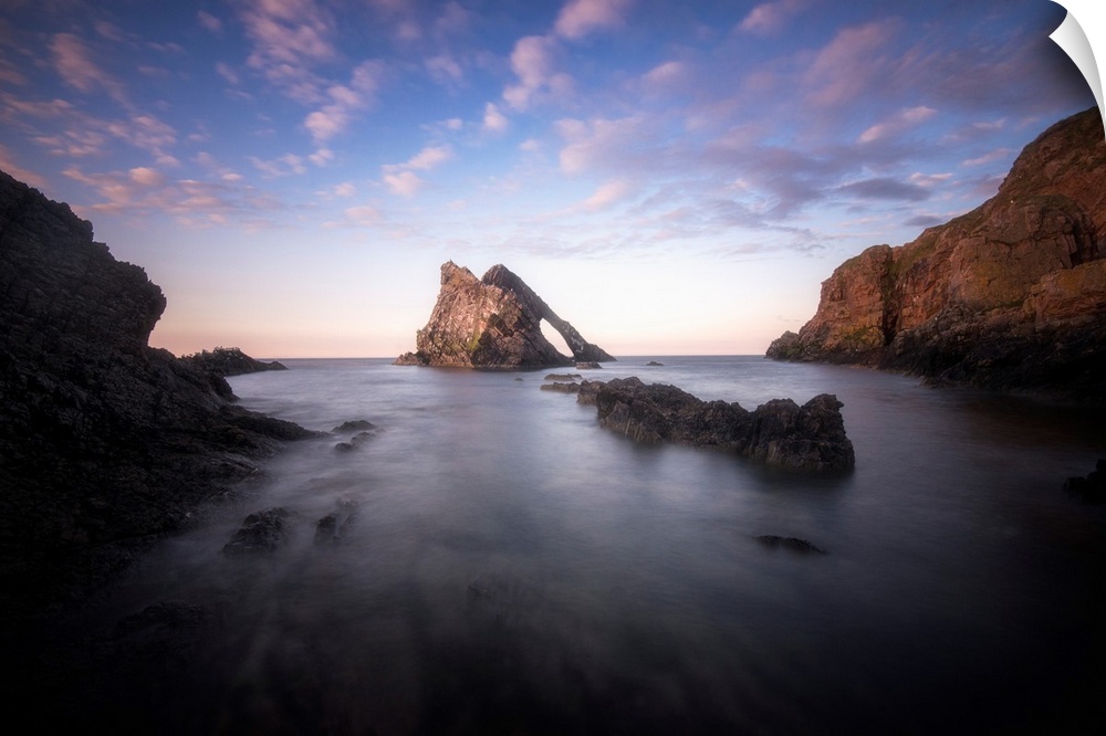 Natural arch Rock in the middle of the sea at sunset in scotland north coast