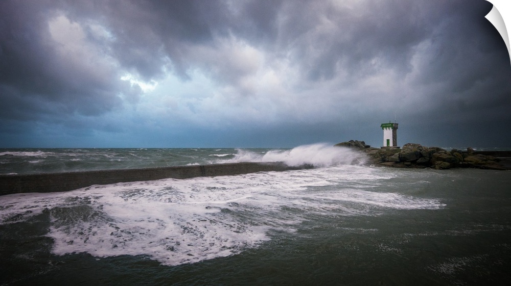 A photograph of the French coast with a lighthouse in the distance under a sky filled with ominous clouds.