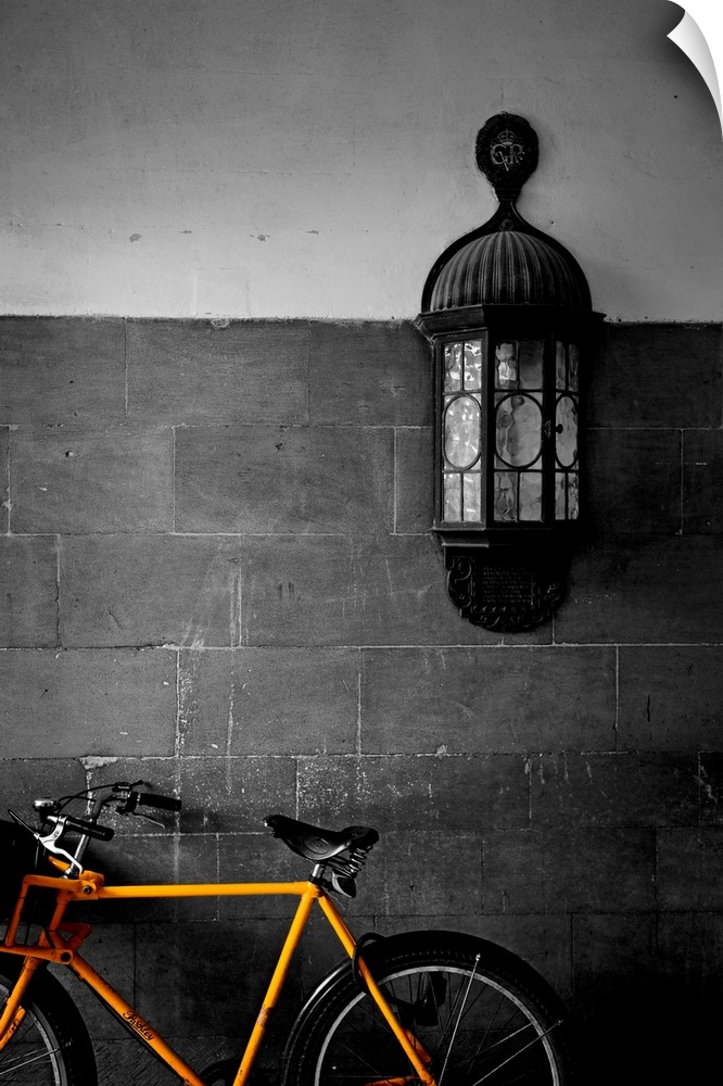 Contemporary photograph of brightly colored bicycle with antique light fixture on brick wall in background.