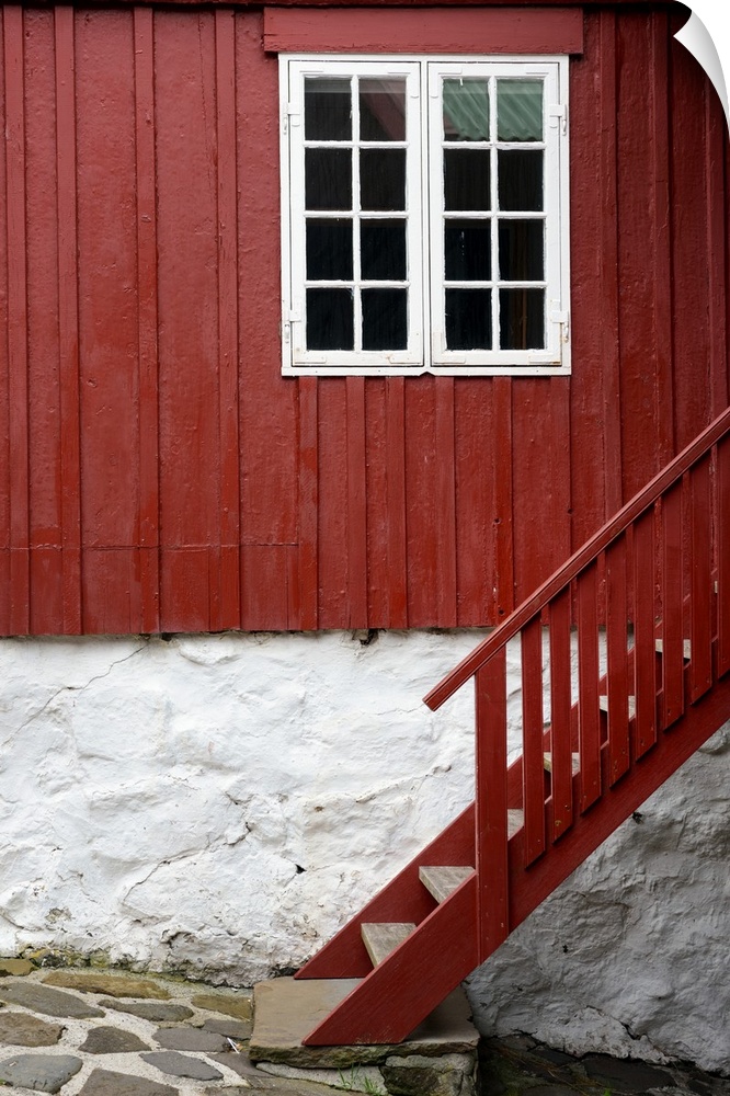 A red staircase against a house with a white framed window.