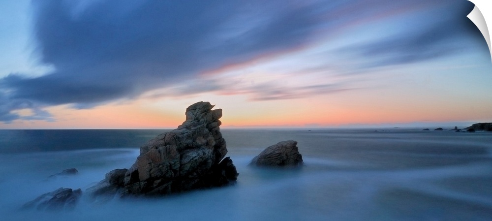 Pink and blue sunset on a shorecoast in Brittany in France, Quiberon area called cote sauvage, during summer, two rocks in...