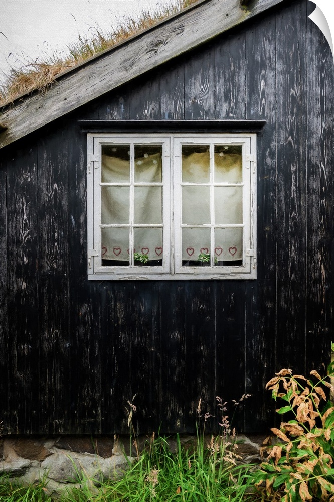 A window with white frames in the black wall of a house.