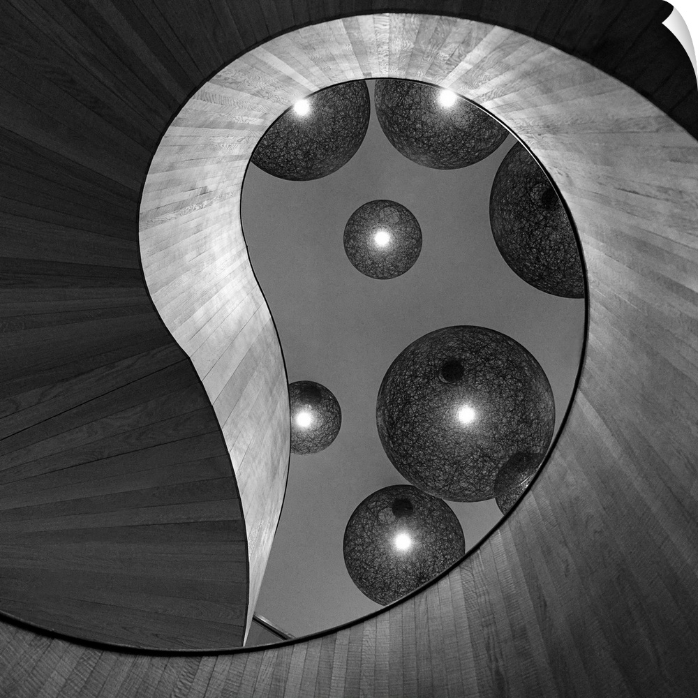 Black and white abstract photograph of large and small spheres hovering around an organic architectural structure.