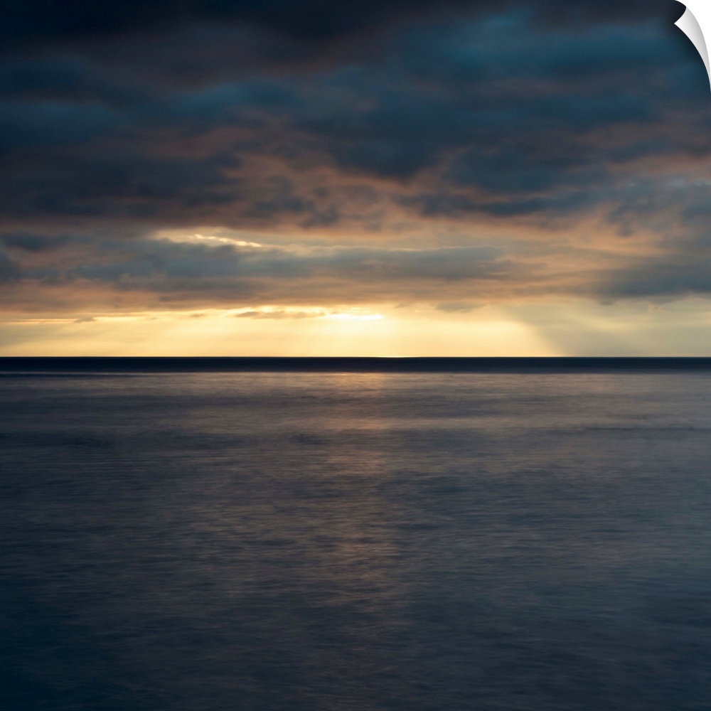 A dramatic dark golden dawn seascape over a still sea.
