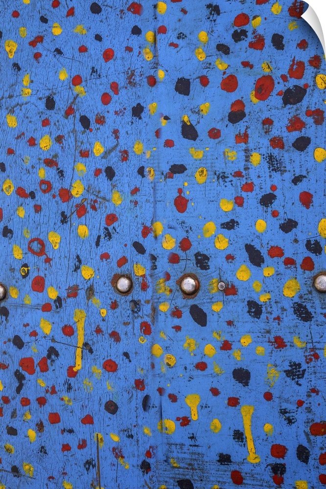 Abstract artwork of yellow and red dots splattered on blue doors.