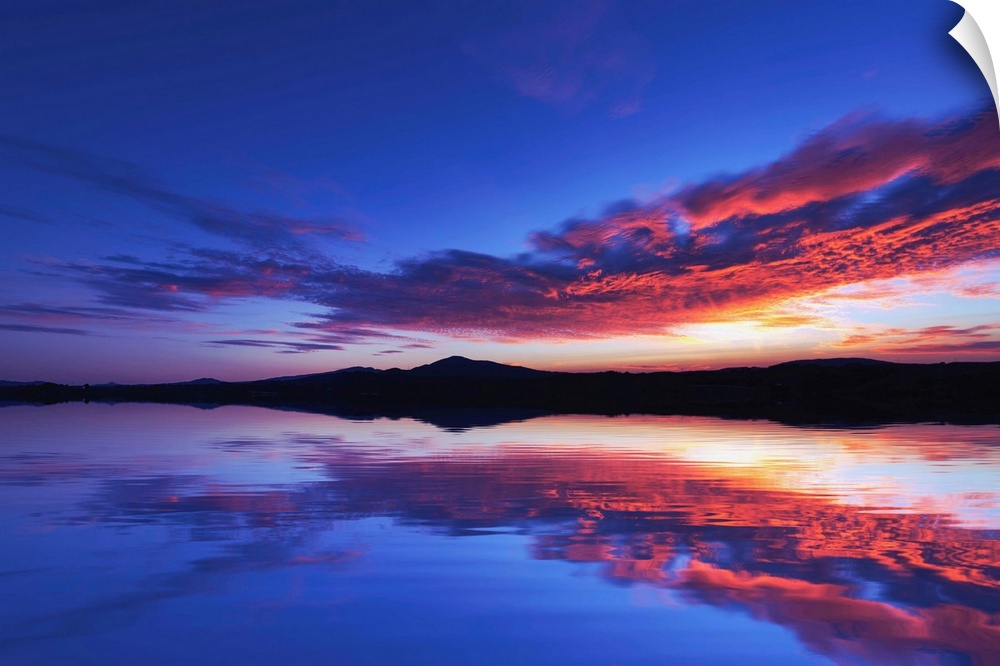 Reflection of a sunset over the sea with mountains in the background
