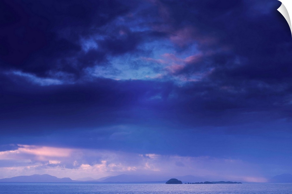 Fine art photo of a deep blue sky with storm clouds over the ocean.