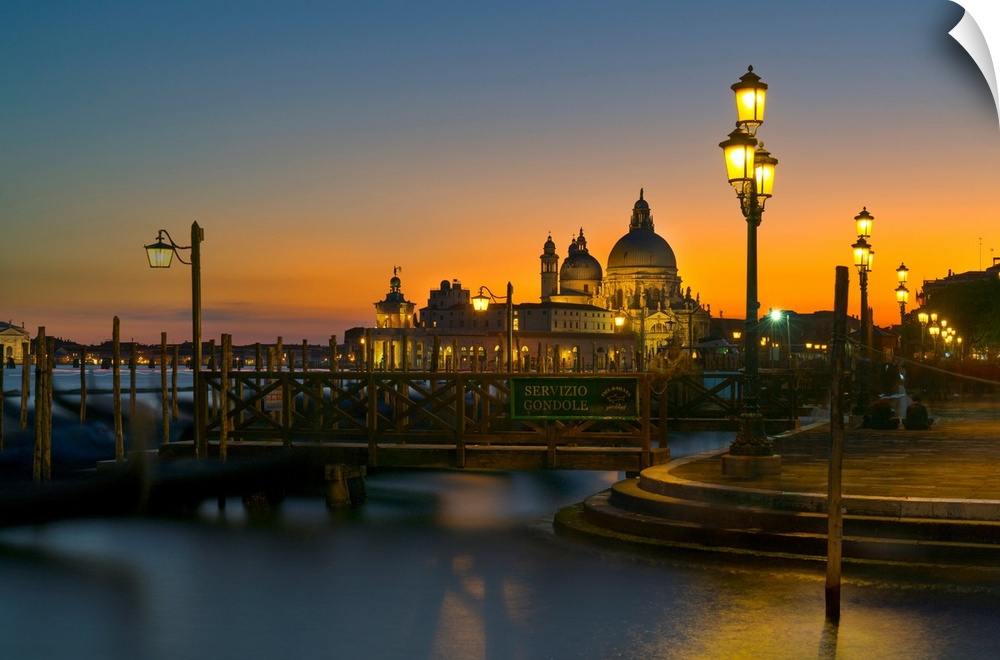 Sunset over Venice, Italy with yellow lit lampposts and calm waters.