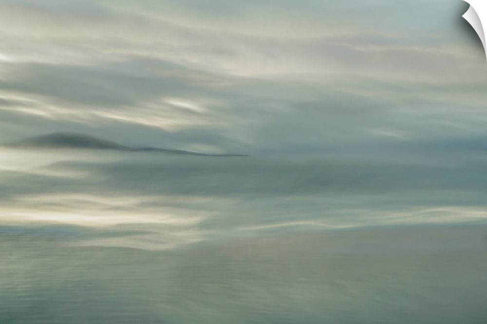 Abstract fine art photograph of a dreamy ocean and a darker silhouetted island in the distance.
