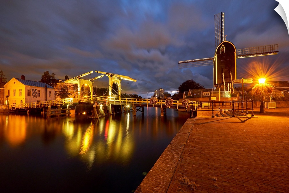 View of a canal with a small bridge and windmill at night, Leiden, South Holland, Netherlands.