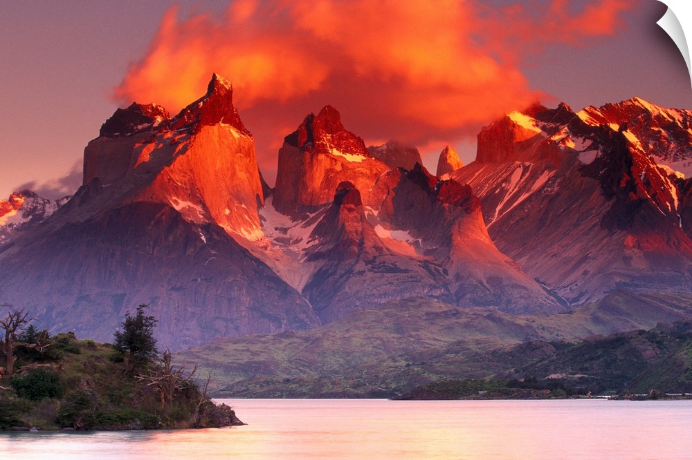This breathtaking view is of immense mountains that have warm tones at the very top from the sunset sky above.