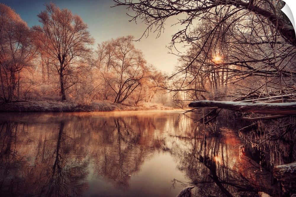 In this landscape photograph morning light reflects off a river in a forest covered with the first frost.