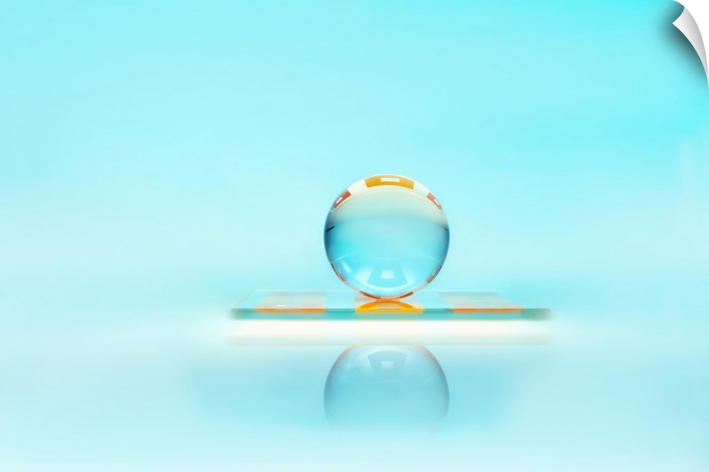 A clear glass sphere resting against a turquoise backdrop.