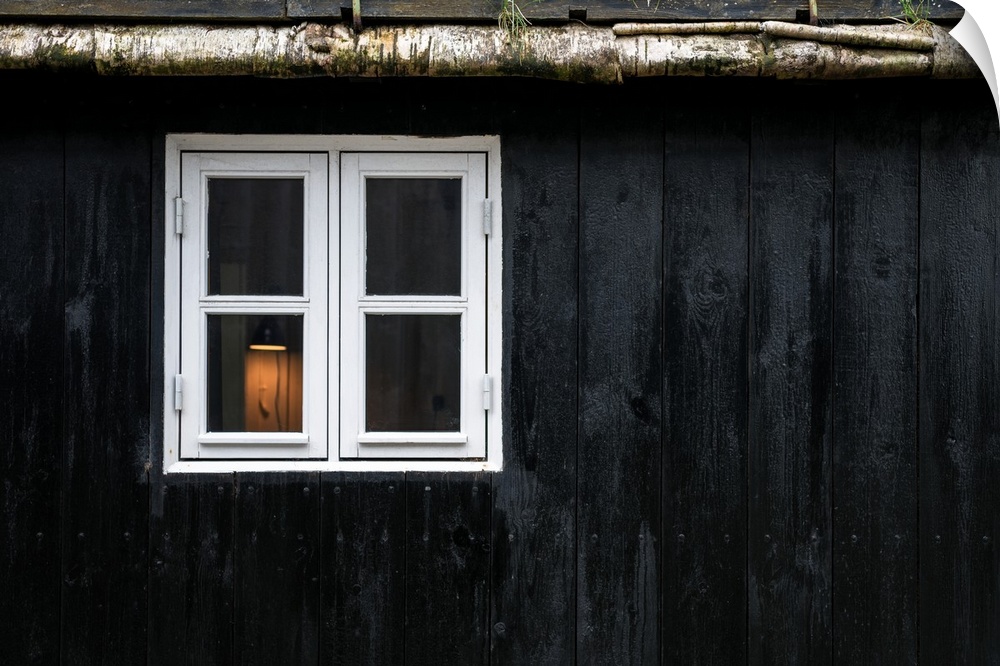 Light in a window with a white frame in a black painted wall.
