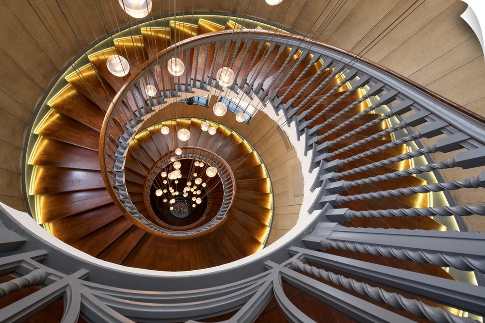 View down the center of a spiral staircase with hanging lights.