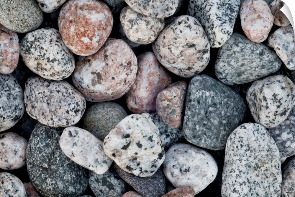 A close up of pale contemporary granite pebbles on a beach.