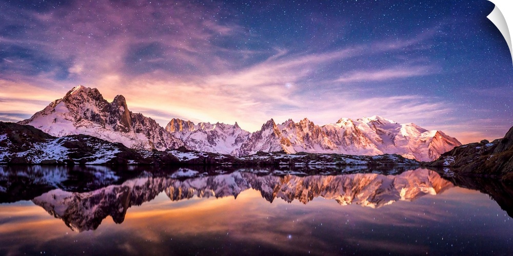 Fine art photograph of a snowy mountain range reflected in the water under a lavender sky in France.