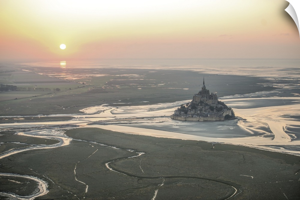 Mont Saint Michel in France at low tide under the setting sun.