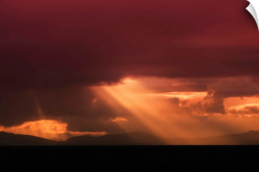Fine art photo of a bright beam of light shining through the clouds at sunset.