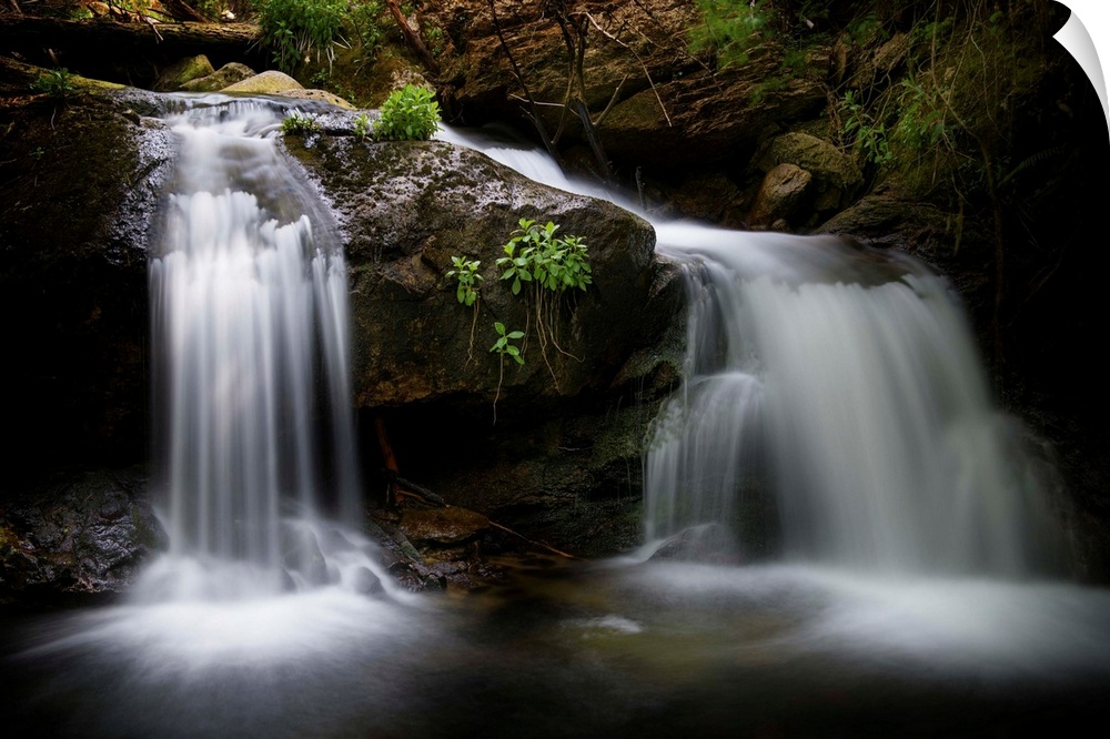 A photograph of a waterfall streaming down rocks in a forest.