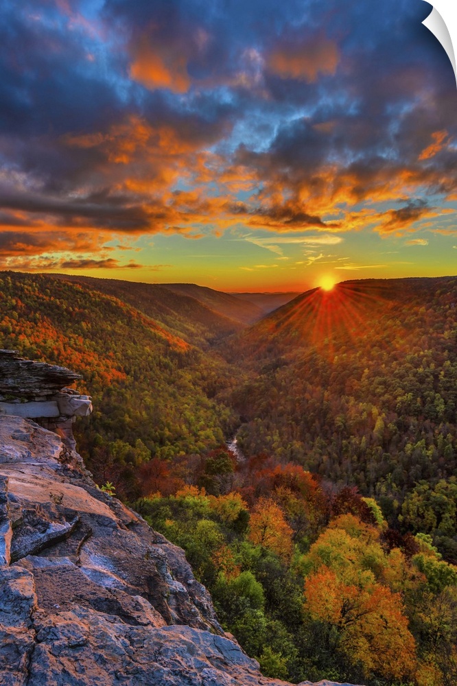 The sun on the horizon casting a vivid glow in the clouds over a dense forest in West Virginia.