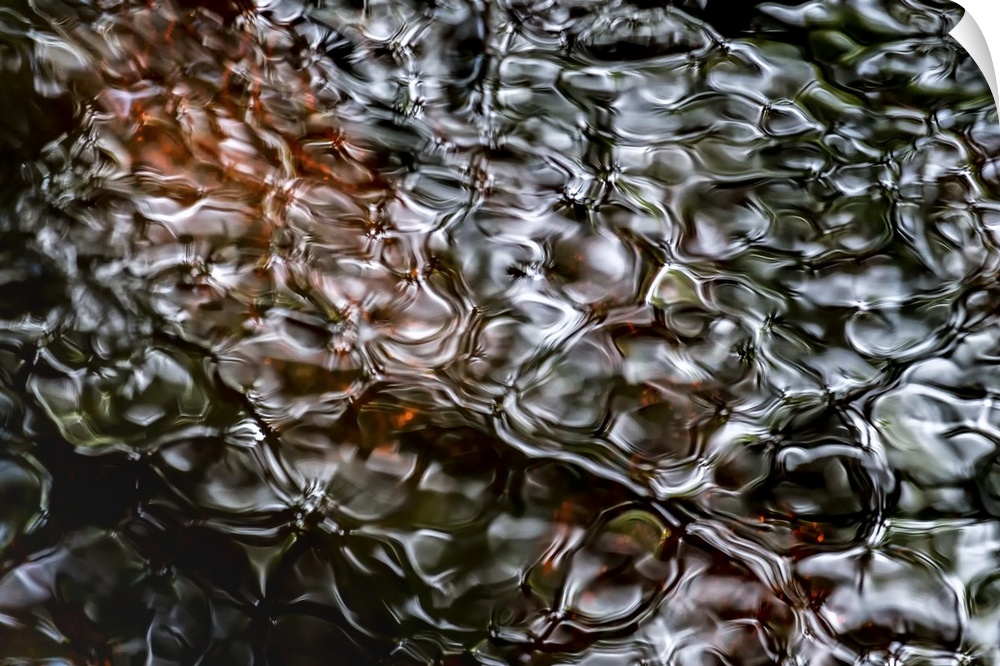 A photograph of a close-up of rippled water with a dark brown peering through the surface.