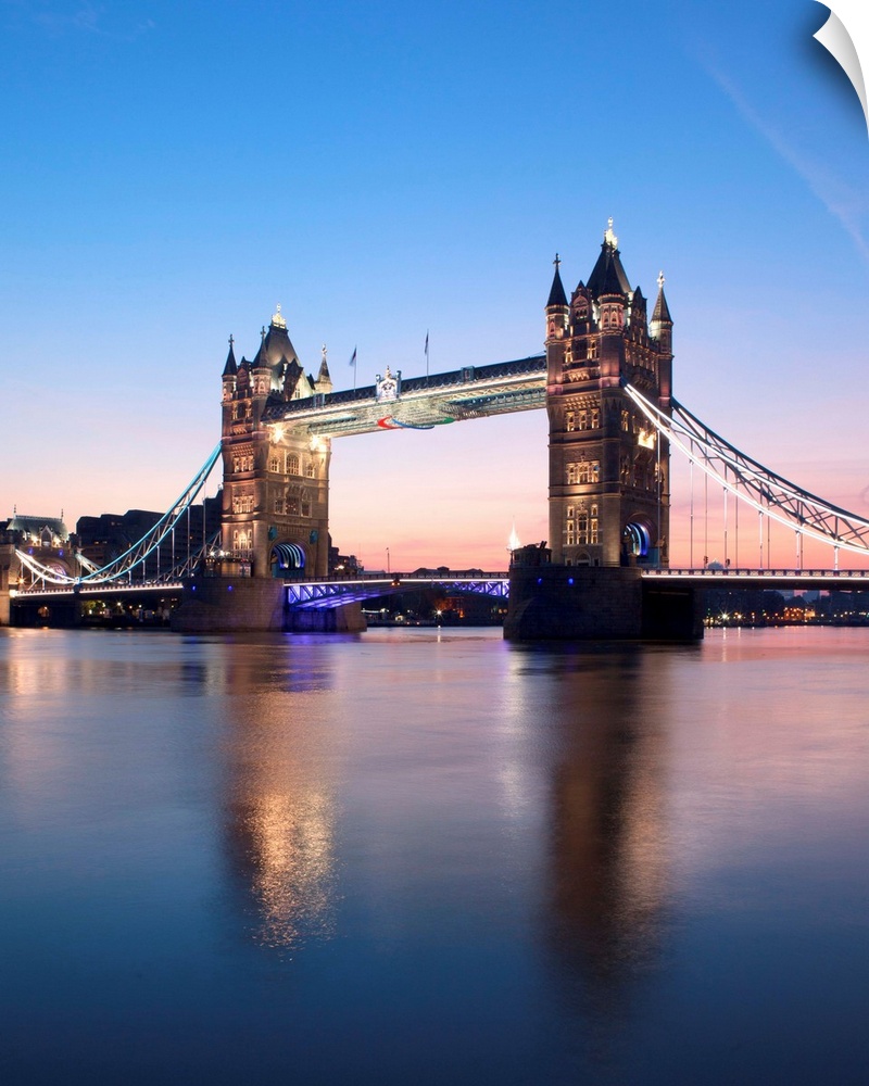 Tower Bridge, London, UK at sunrise with a clear blue sky and reflections in the River Thames.