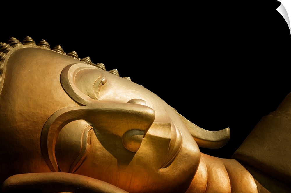 The head of a reclining Buddha in front of a black background