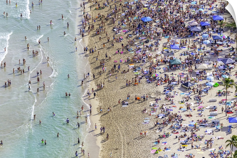 Aerial view of hundreds of beachgoers in the sand and turquoise waters of Miami Beach in Florida.