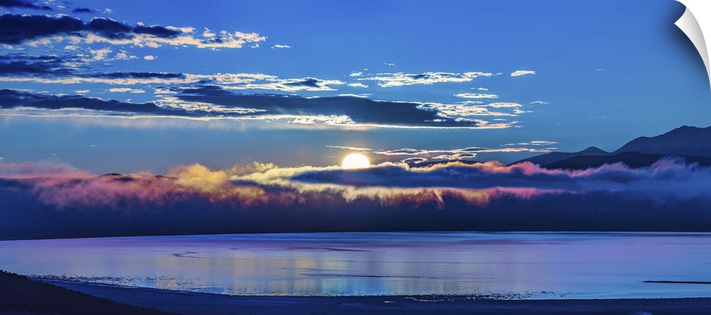 The sun peeking behind the clouds at dawn over Mono Lake, California.
