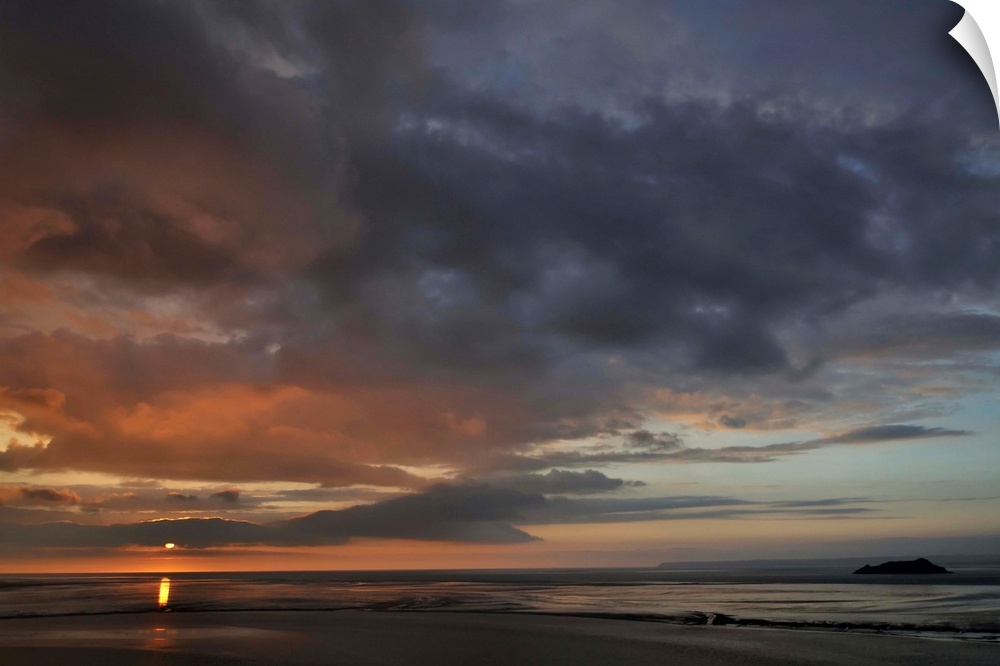 The large bay of Mont Saint Michel area at the end of the day with big clouds and pink sky.