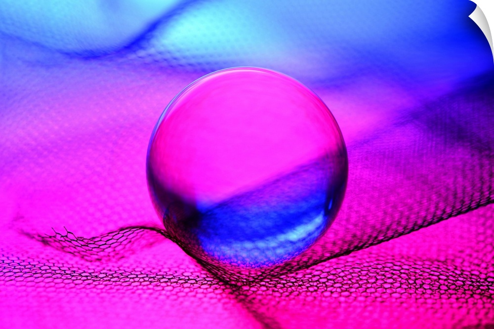 A glass sphere reflecting bright fuchsia and blue light.