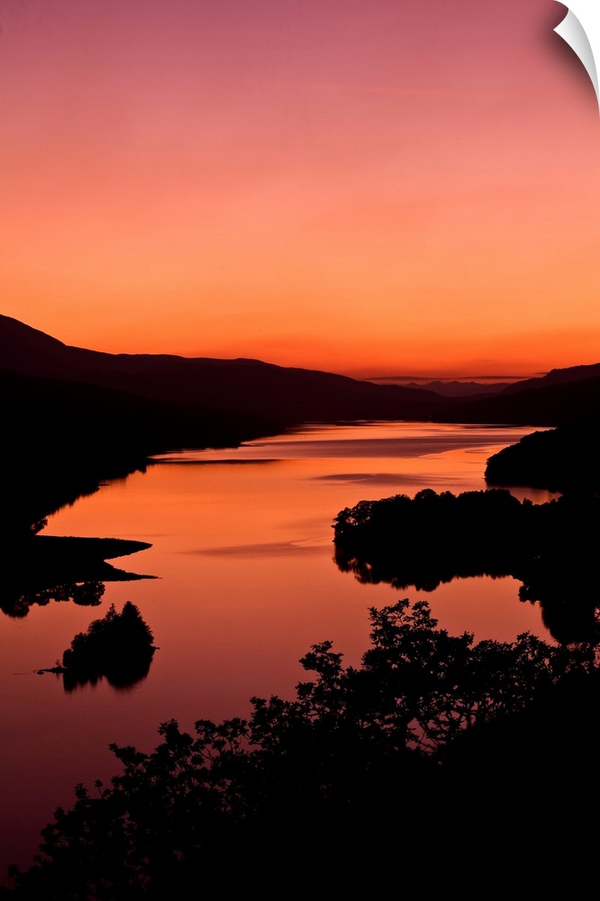 An intense orange sunset landscape view over a loch in Scotland.