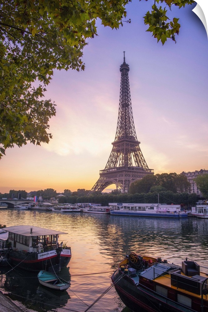Sunrise on the Eiffel tower on summer morning in Paris with Peniche boats waiting on the side of the river. Some trees aro...