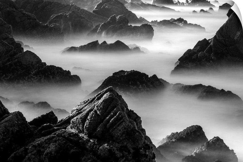 Rocky outcroppings rising above the mist on the coast in Point Lobos, California.