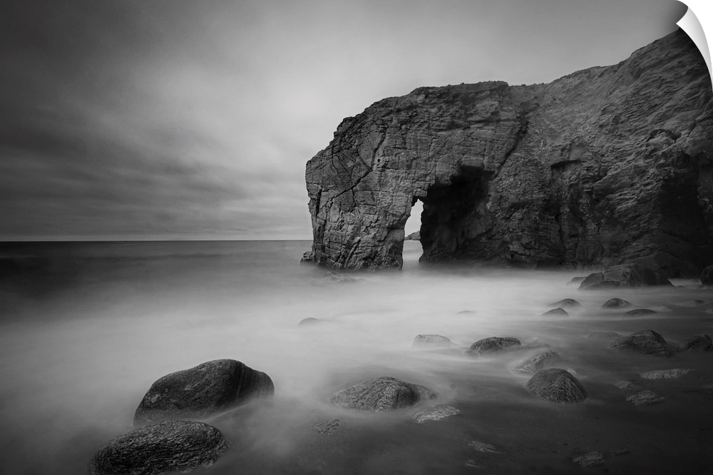 The natural arch rock in Quiberon island in Britany at high tide, a long black and white time exposure, sand beach in Fran...