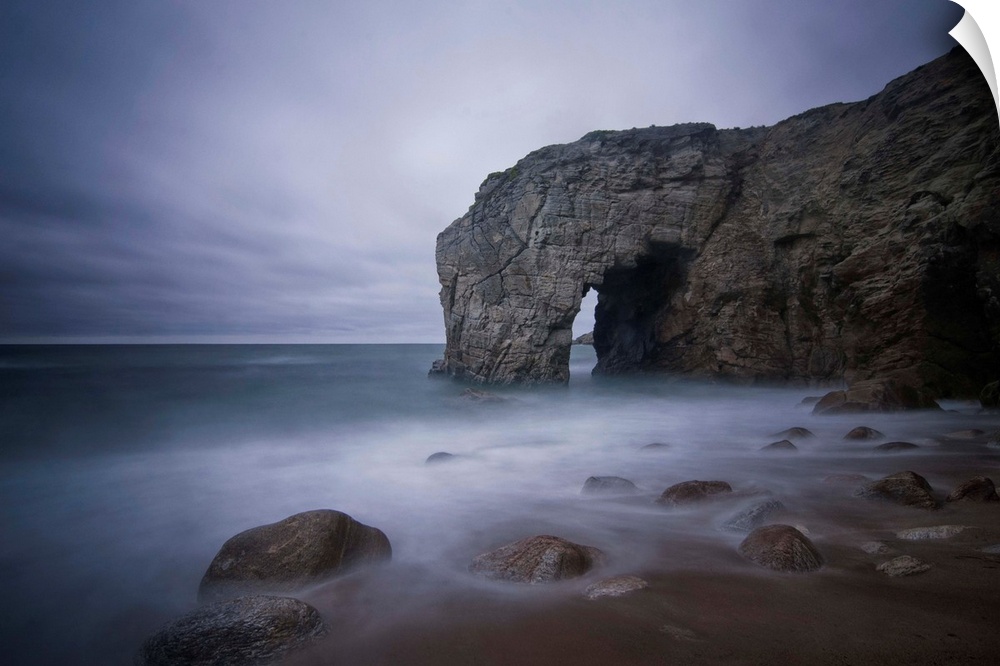 He natural arch rock in Quiberon island in Britany at high tide, a long colored time exposure, sand beach in France on the...