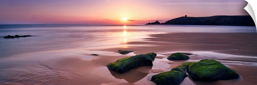 Panoramic beach with rocks during a pink quite sunset in Brittany, France.