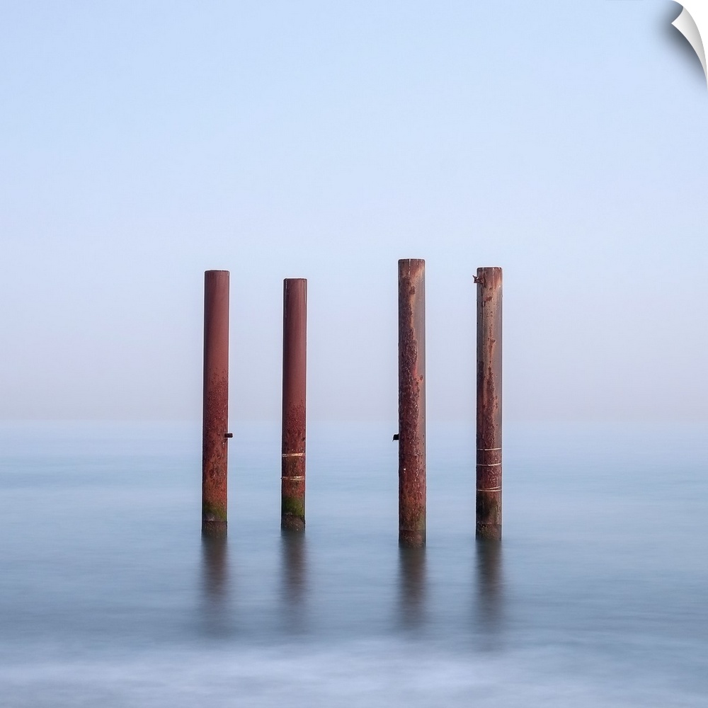 Four wooden posts standing in flowing water.