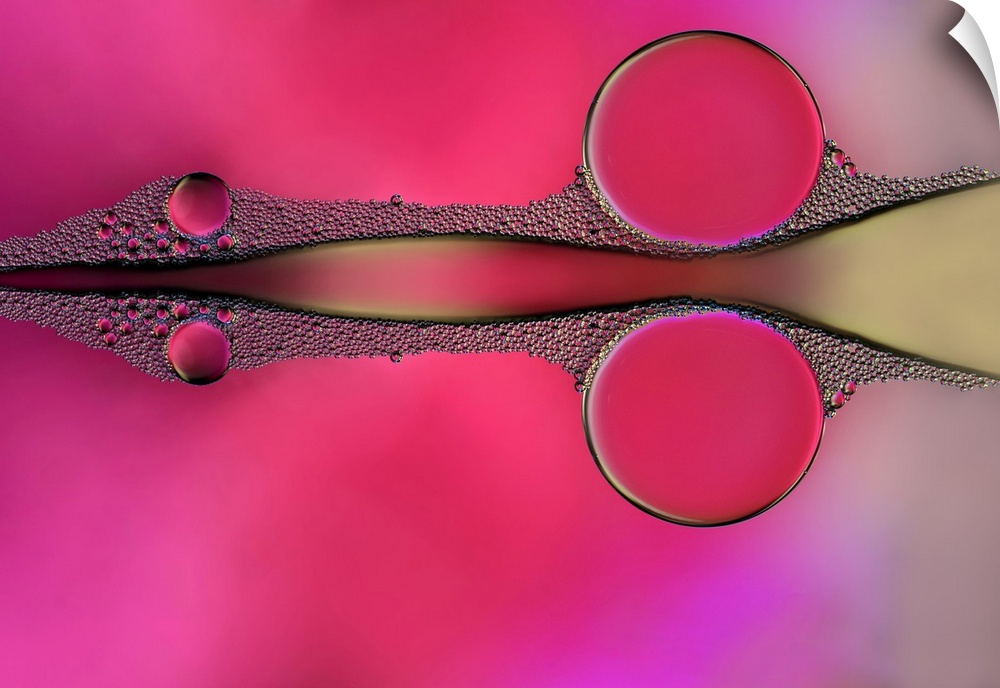 Reflecting drops of water on a pink, purple, and yellow background, resembling a scissor shape.