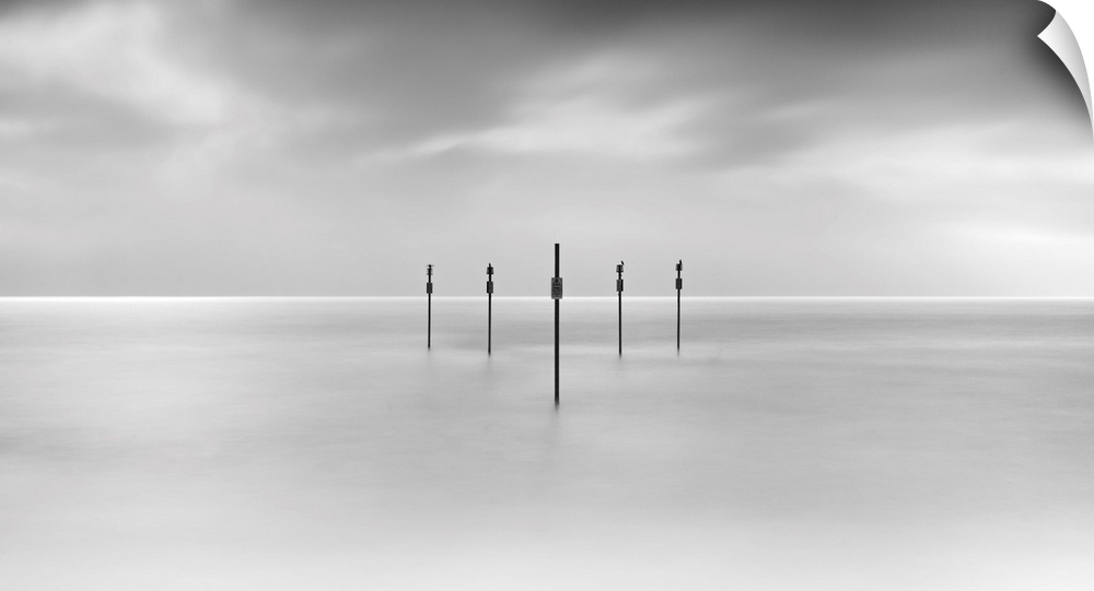 Minimal panoramic monochrome black and white zen calm seascape with five poles in the flat sea.