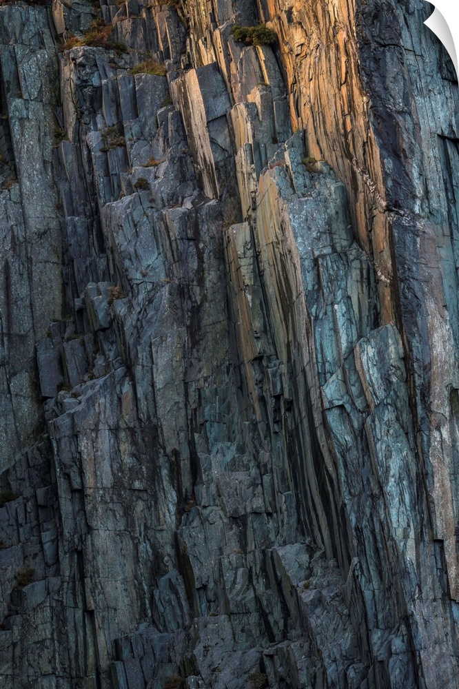 Fine art photo of a very steep cliff face, with a little glow on the rocks.