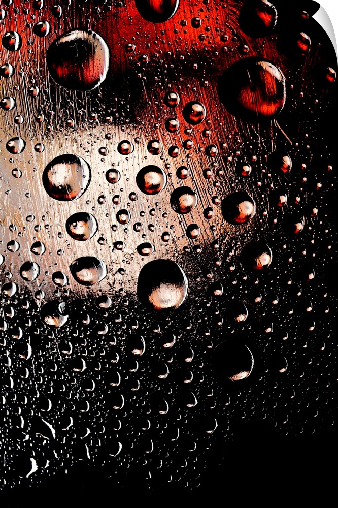 A photo of raindrops sitting on a window with red and white lights shining behind.